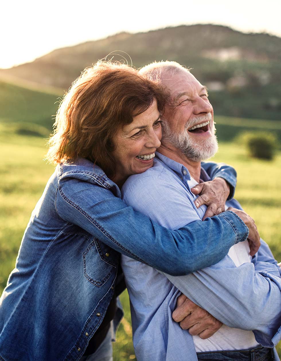 senior couple hugging outdoors with mountains in background keys to a successful retirement