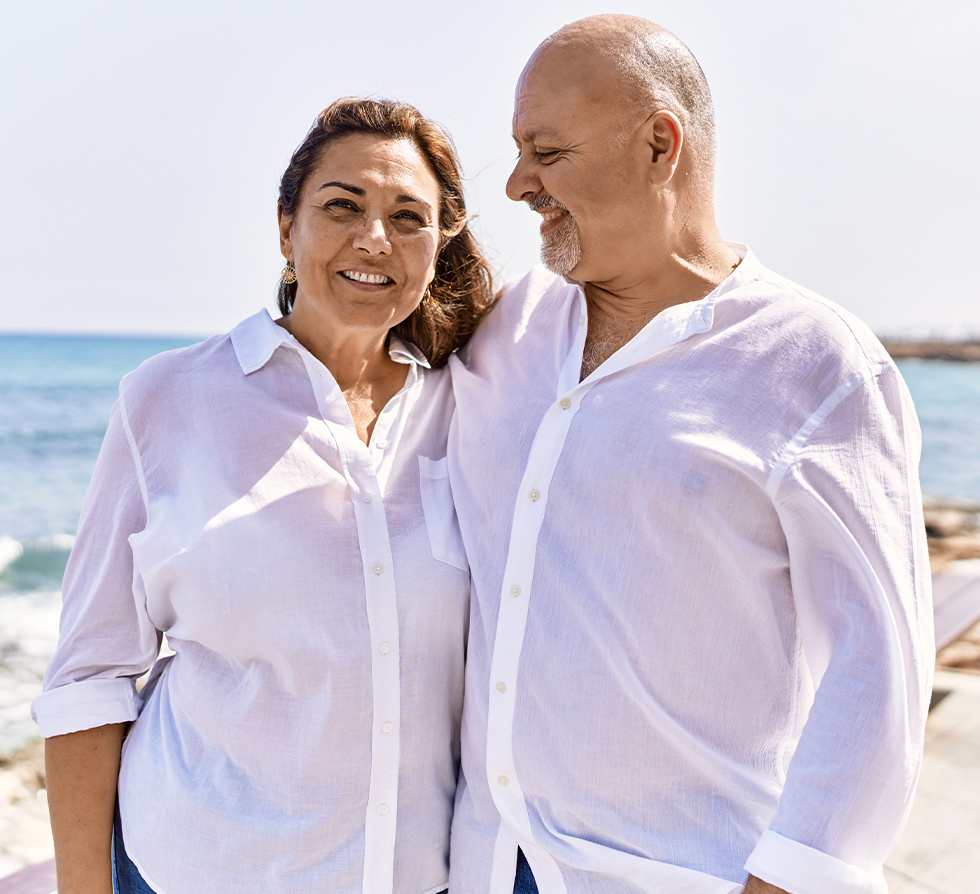 smiling middle aged couple on beach reasonable rate of return in retirement suncrest wealth management tucson az
